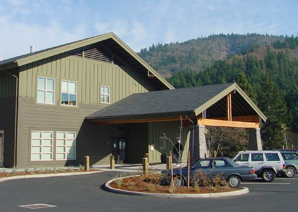 Cars parked in front of a large green and brown building.