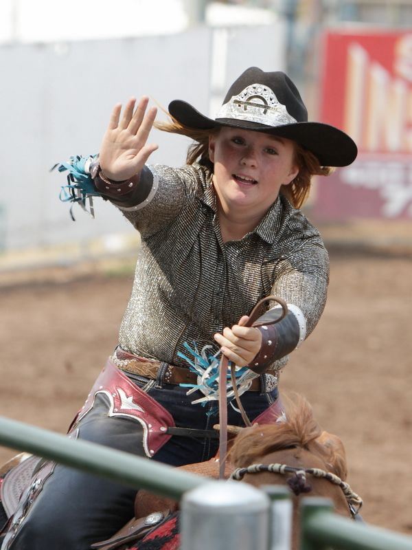 A member of the Rodeo Royal Court waves as she rides by on her horse.