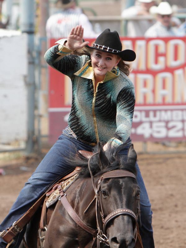 A member of the Rodeo Royal Court waves as she rides by on her horse.