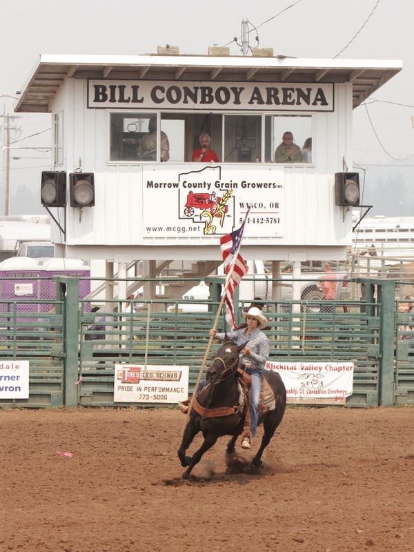 Girl rides her horse and holds out the American Flag.
