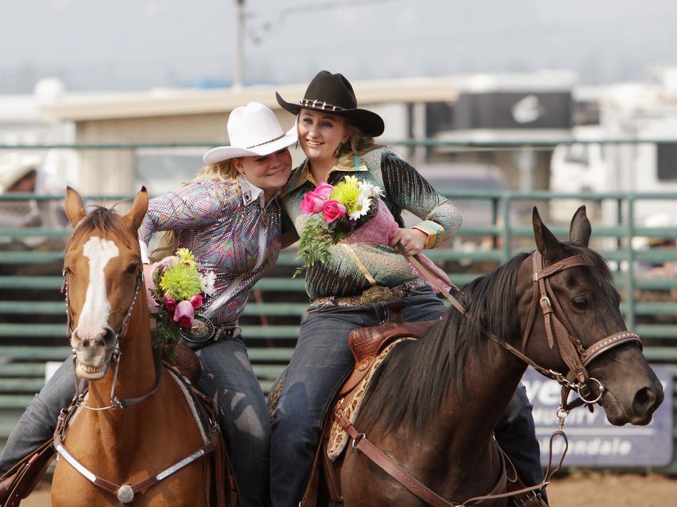 Two of the members of the Rodeo Royalty Court embrace in a hug while still atop their horses.