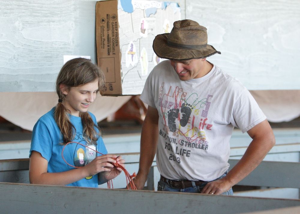 A man and girl stand in a pen at the 2014 Klickitat County Fair.