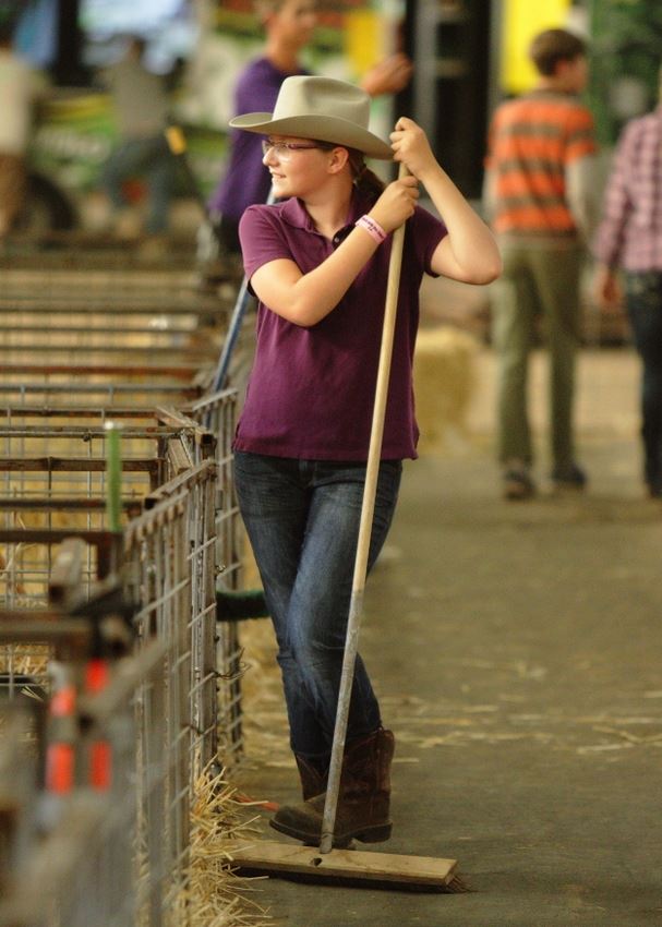 A girl sweeps up in the an animal barn at the 2014 Klickitat County Fair.