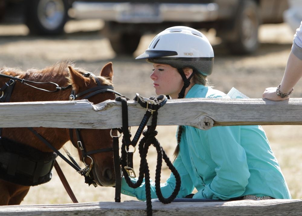 A girl kneels next to a pony at the 2014 Klickitat County Fair.