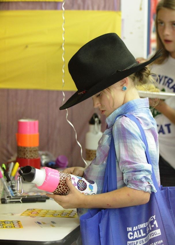 A little girl decorates her reusable water bottle.
