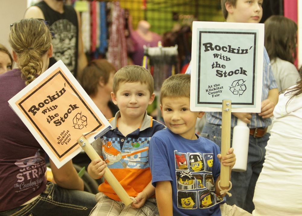 Two little boys hold Rockin' with the Stock signs.