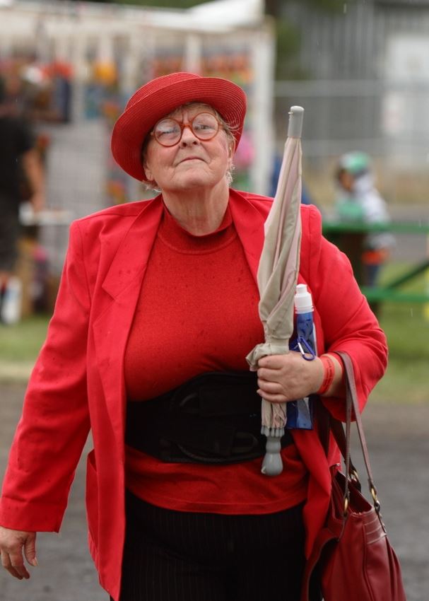 A woman clad in all red holds her umbrella in front of her intently.