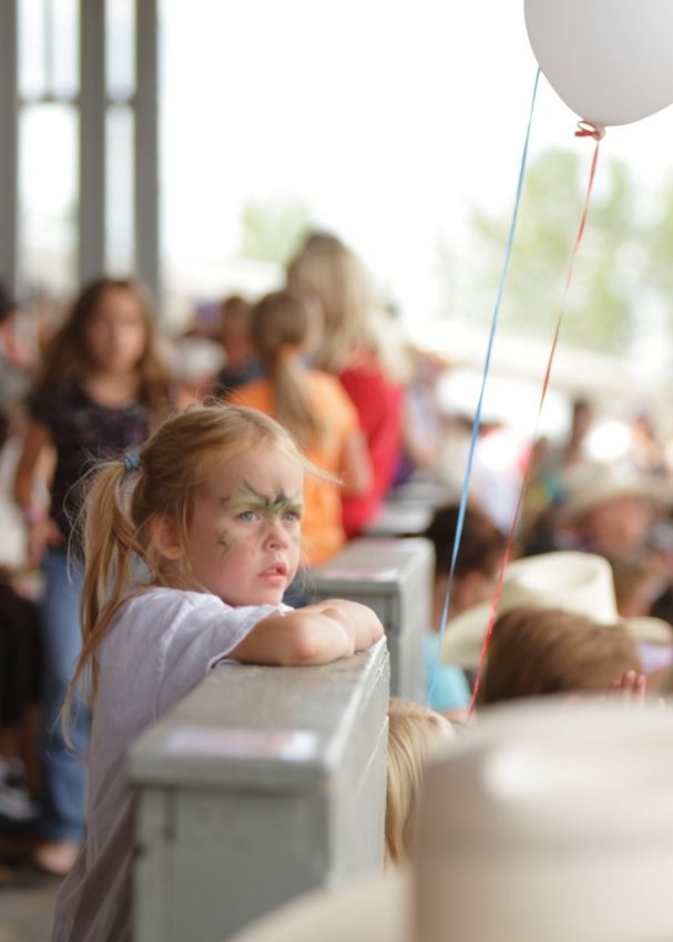 A little girl leans on a fence at the 2014 Klickitat County Fair.