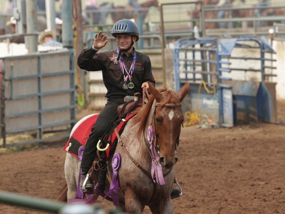 Young man rides his horse and waves to the crowd of the Klickitat County Fair.