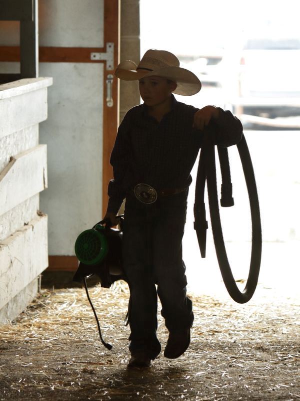 A boy carries some equipment in the animal barn at the Klickitat County Fair.