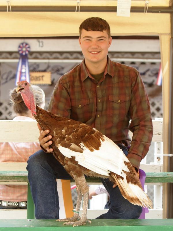 A young man smiles with his prize winning turkey.