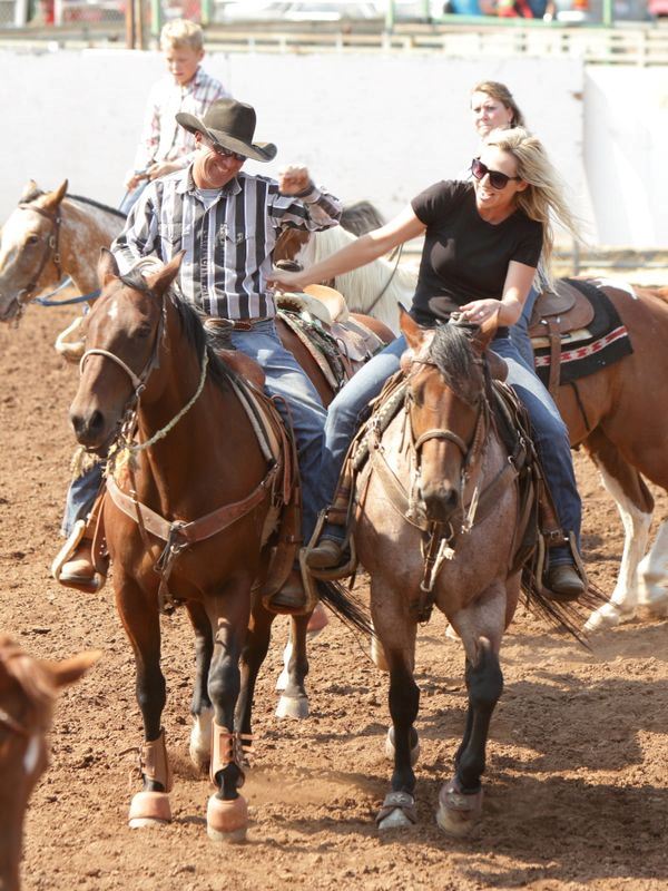 A man and a woman tease one another while riding their horses next to eachother.