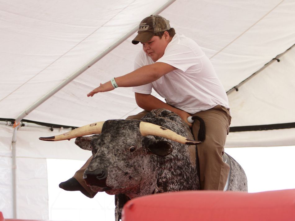 Young man takes his turn at riding the mechanical bull.