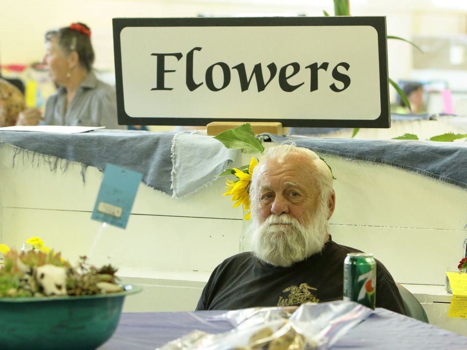 A man sits at a flowers exhibit at the 2015 Klickitat County Fair.