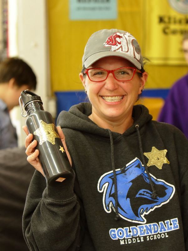 Woman smiles holding her reusable water bottle.