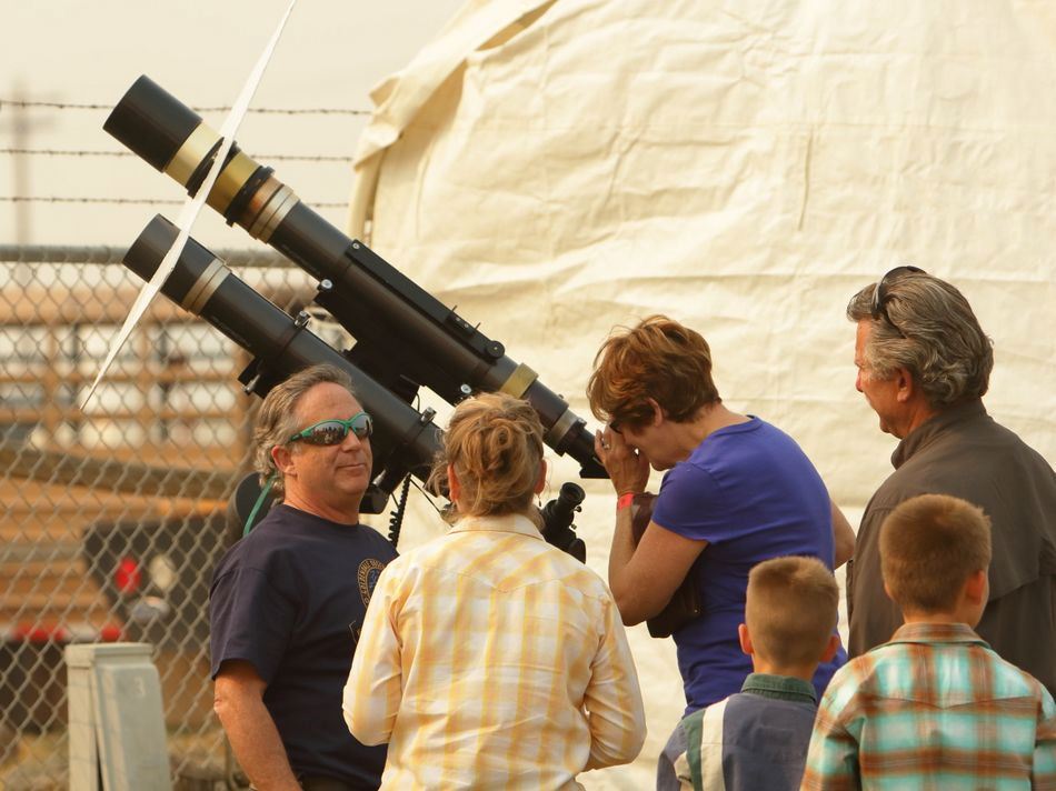 Woman peers through a large telescope at the 2015 Klickitat County Fair.